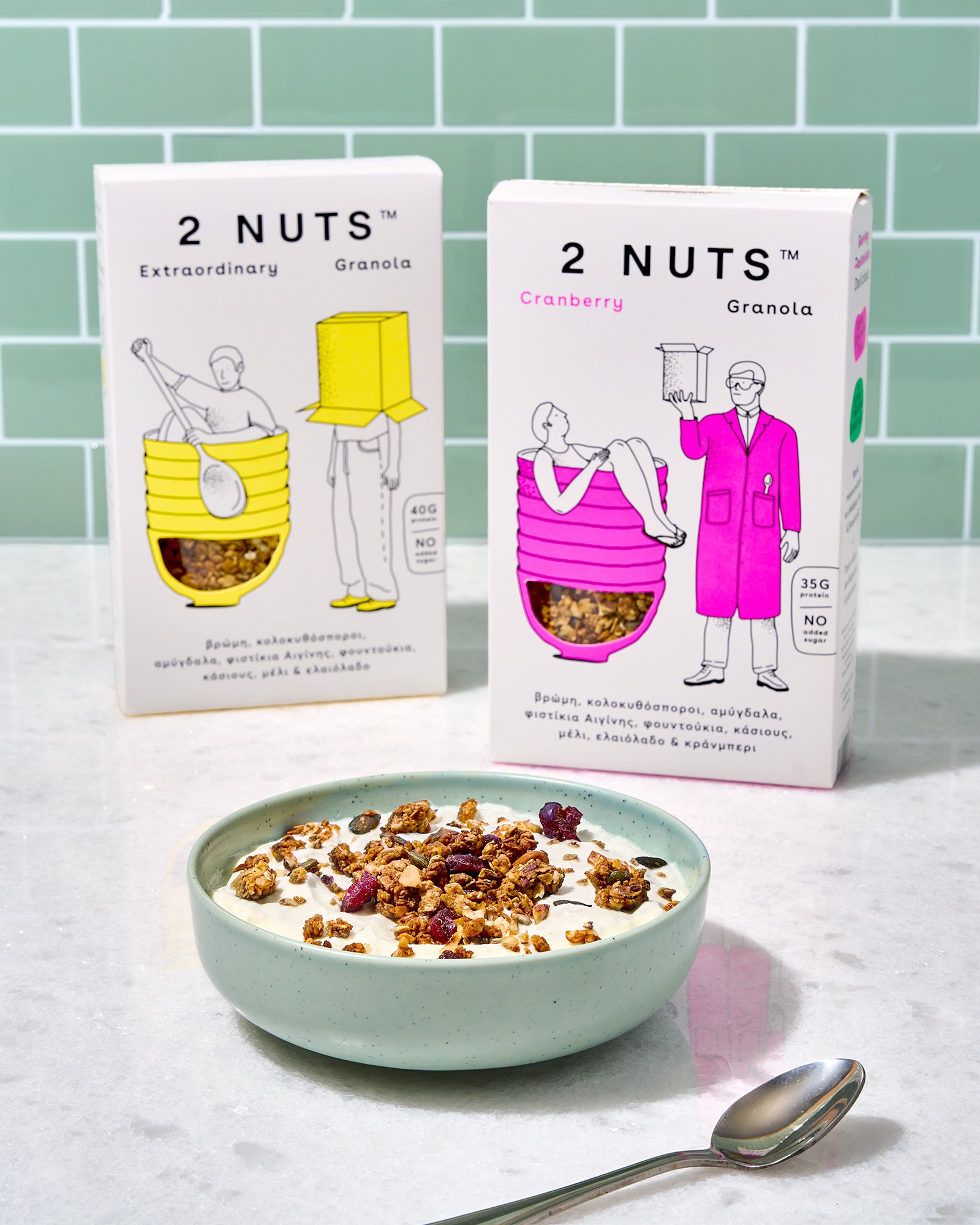 Two 2 NUTS granola boxes behind a bowl of yogurt and granola against mint tiles, photographed for Baransu