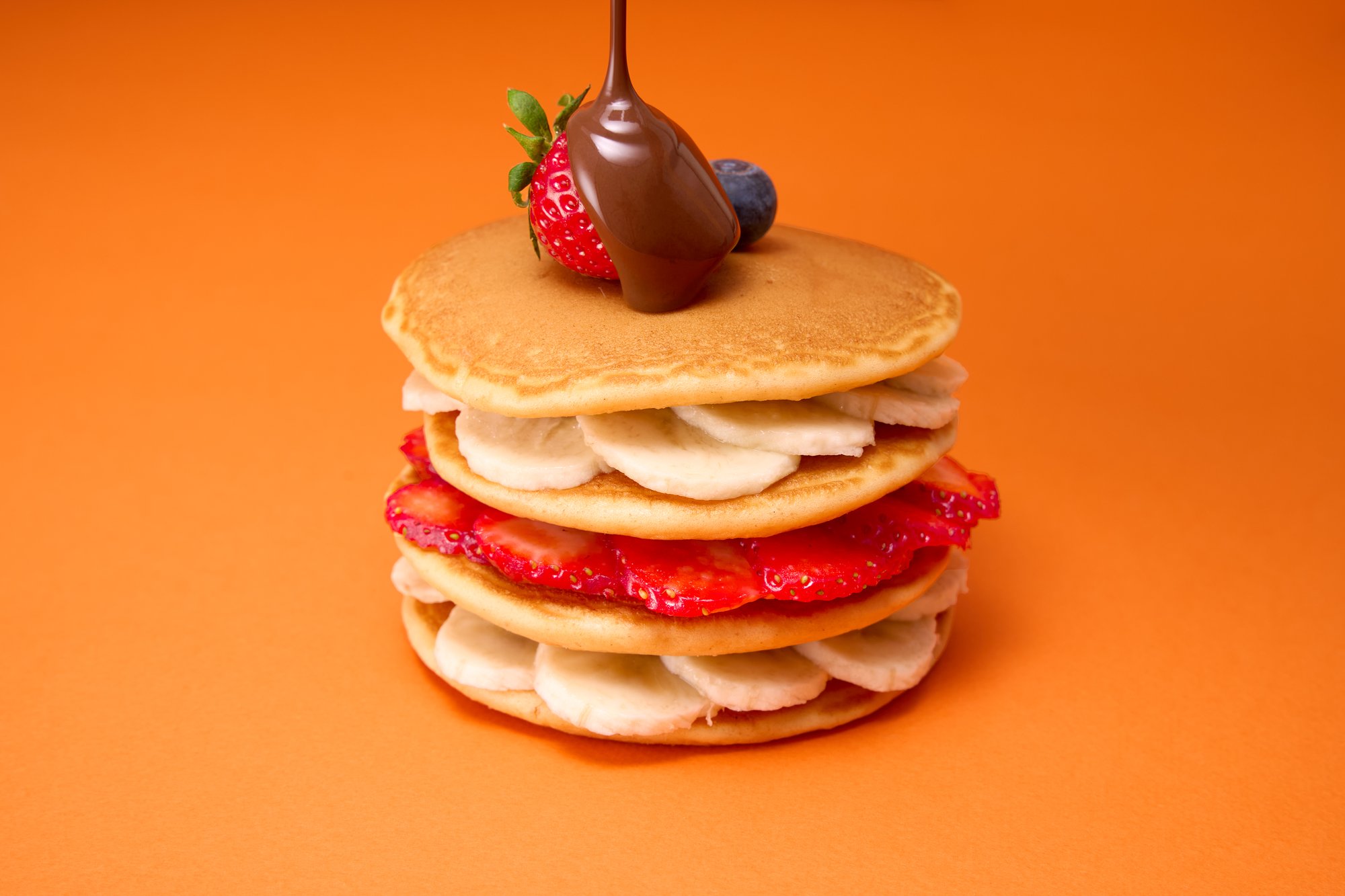 Pancake stack with fruit on orange