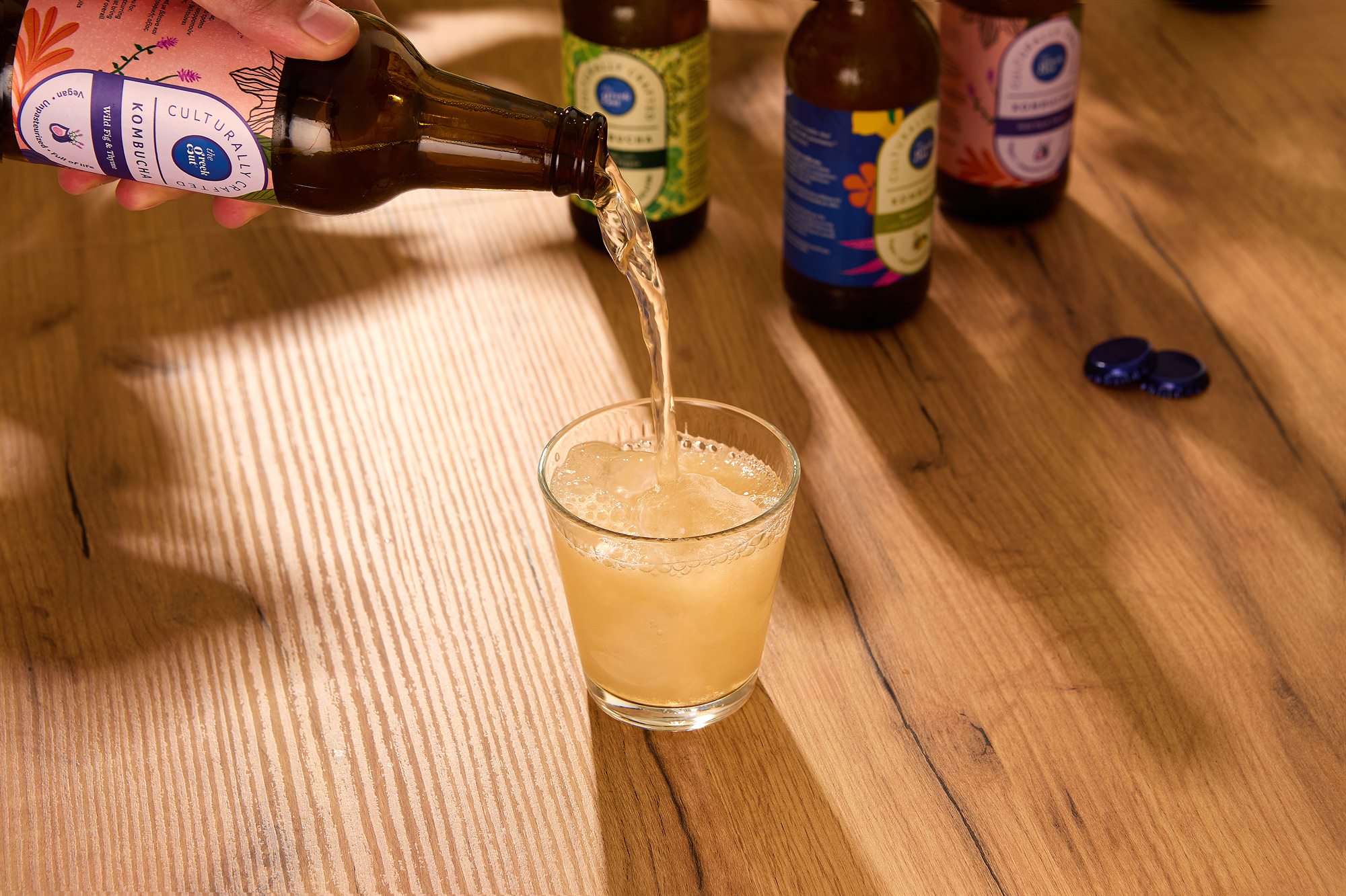 The Greek Gut kombucha being poured into a glass on a wooden table