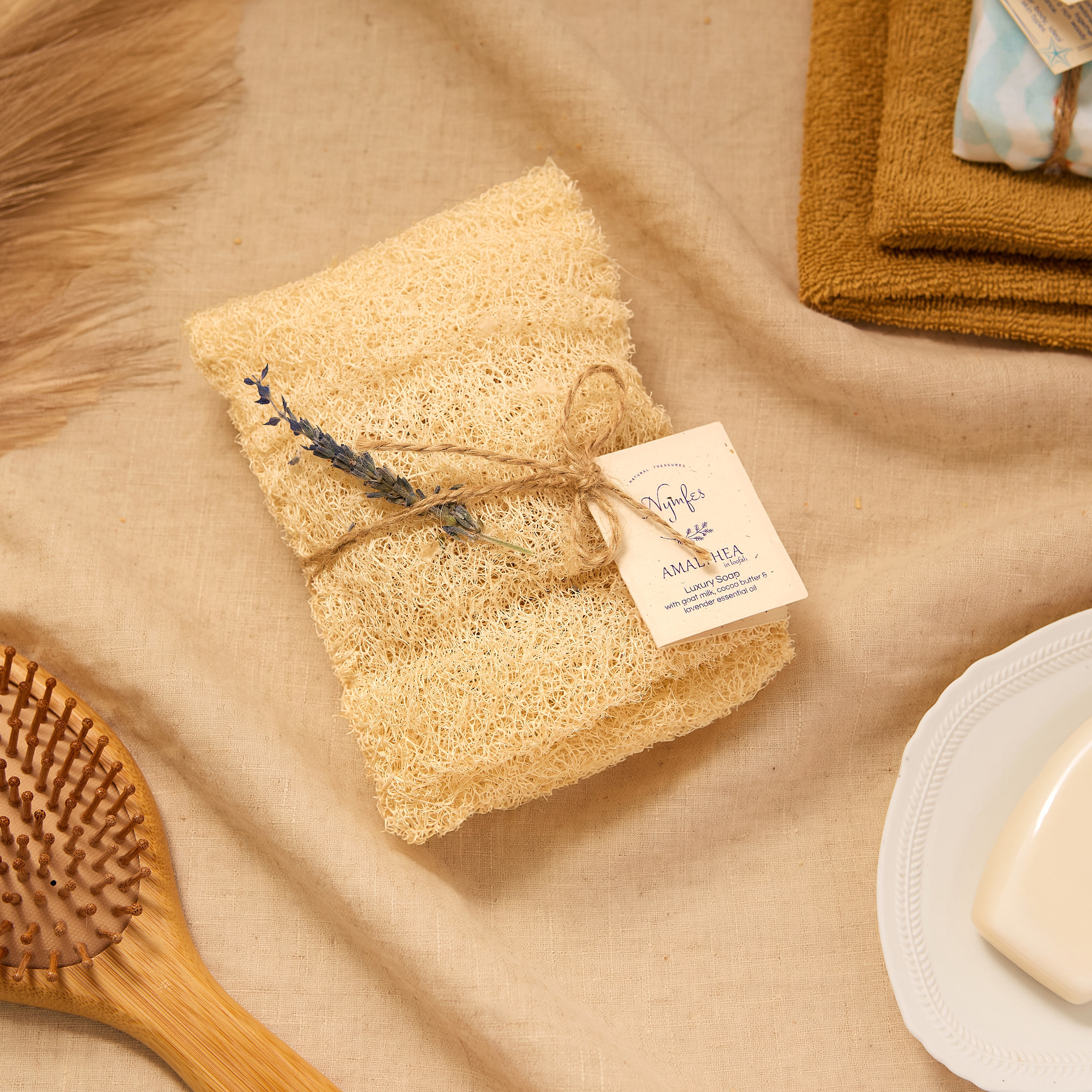 Nymfes Amalthea soap wrapped in loofah, tied with twine and lavender on beige linen